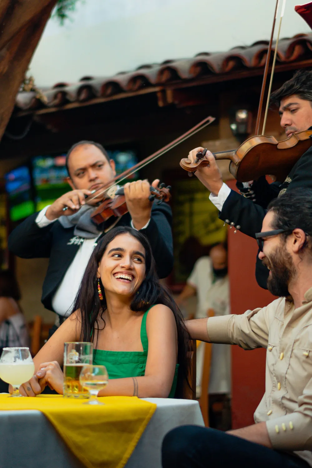 Des convives souriants à table pendant une prestation de violonistes