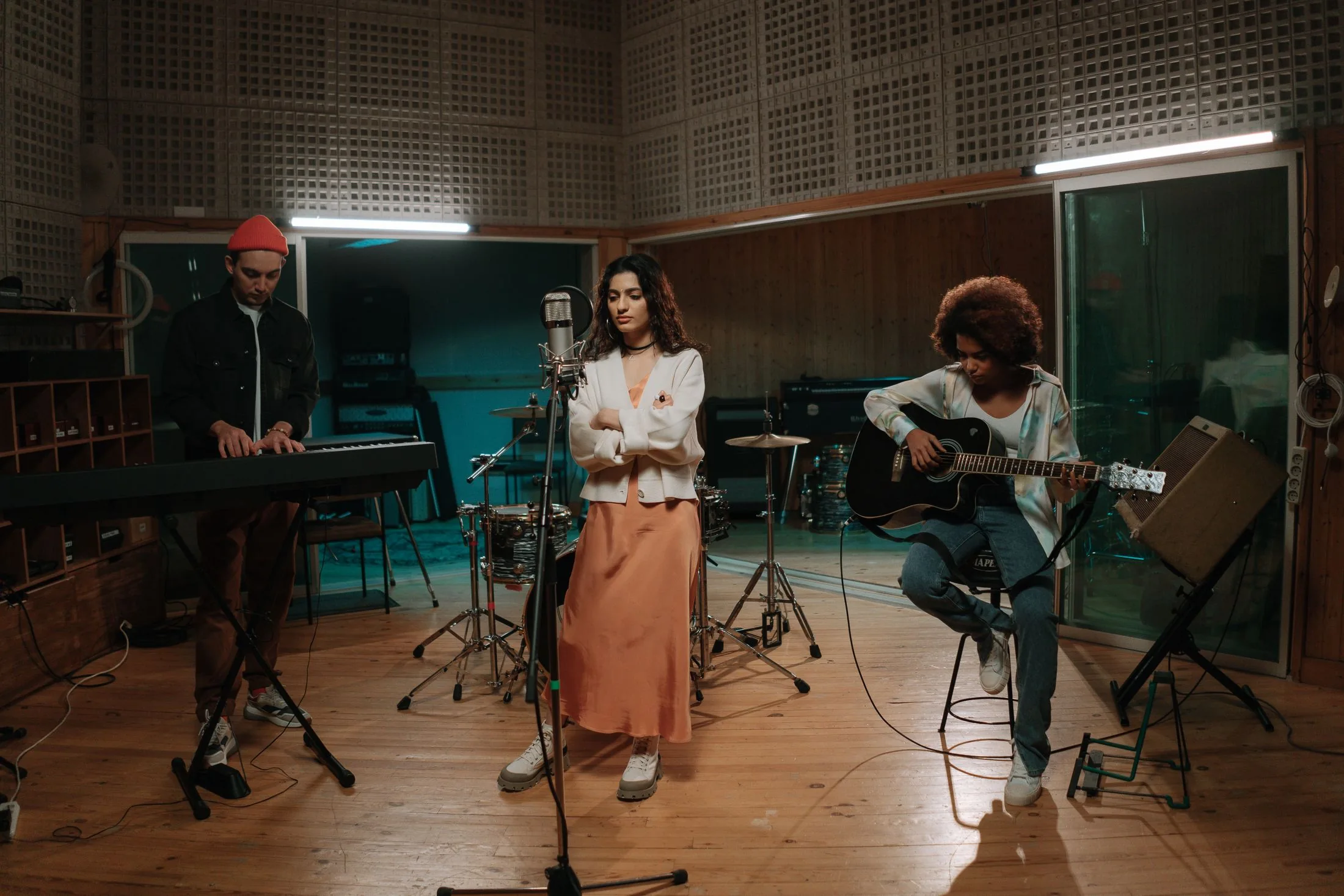 Une chanteuse, un claviériste et une guitariste répètent ensemble