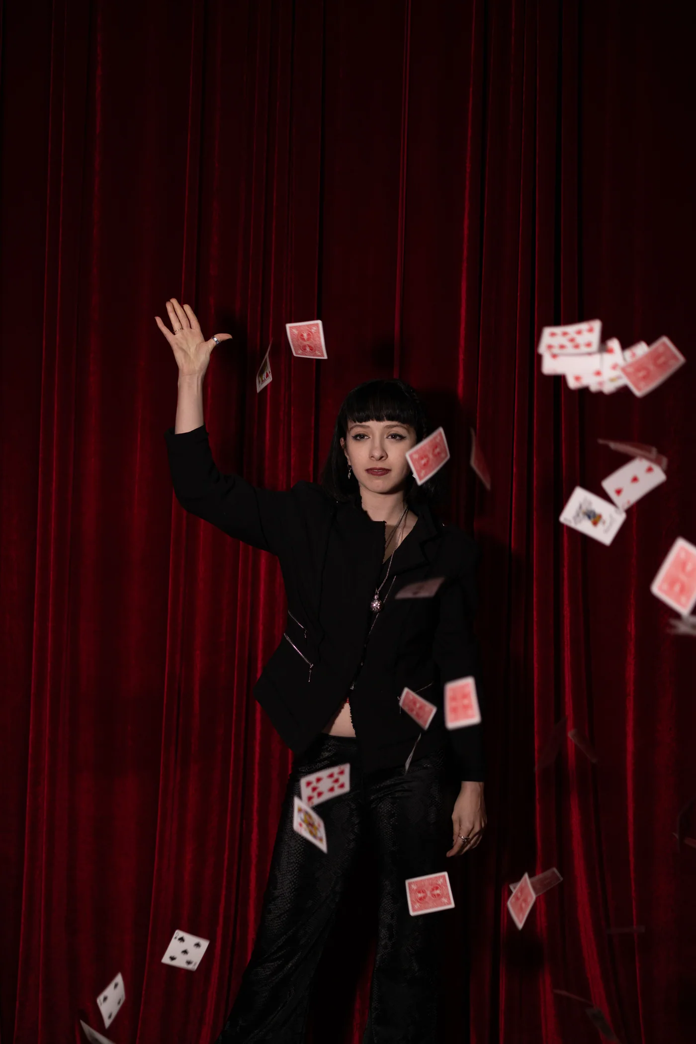 Une illusionniste fait jaillir des cartes devant un rideau de scène